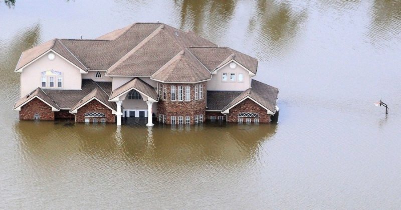 an aerial drone picture of a house in Houston after Hurricane Harvey sitting underwater. Water is coming up almost to the top of the front door
